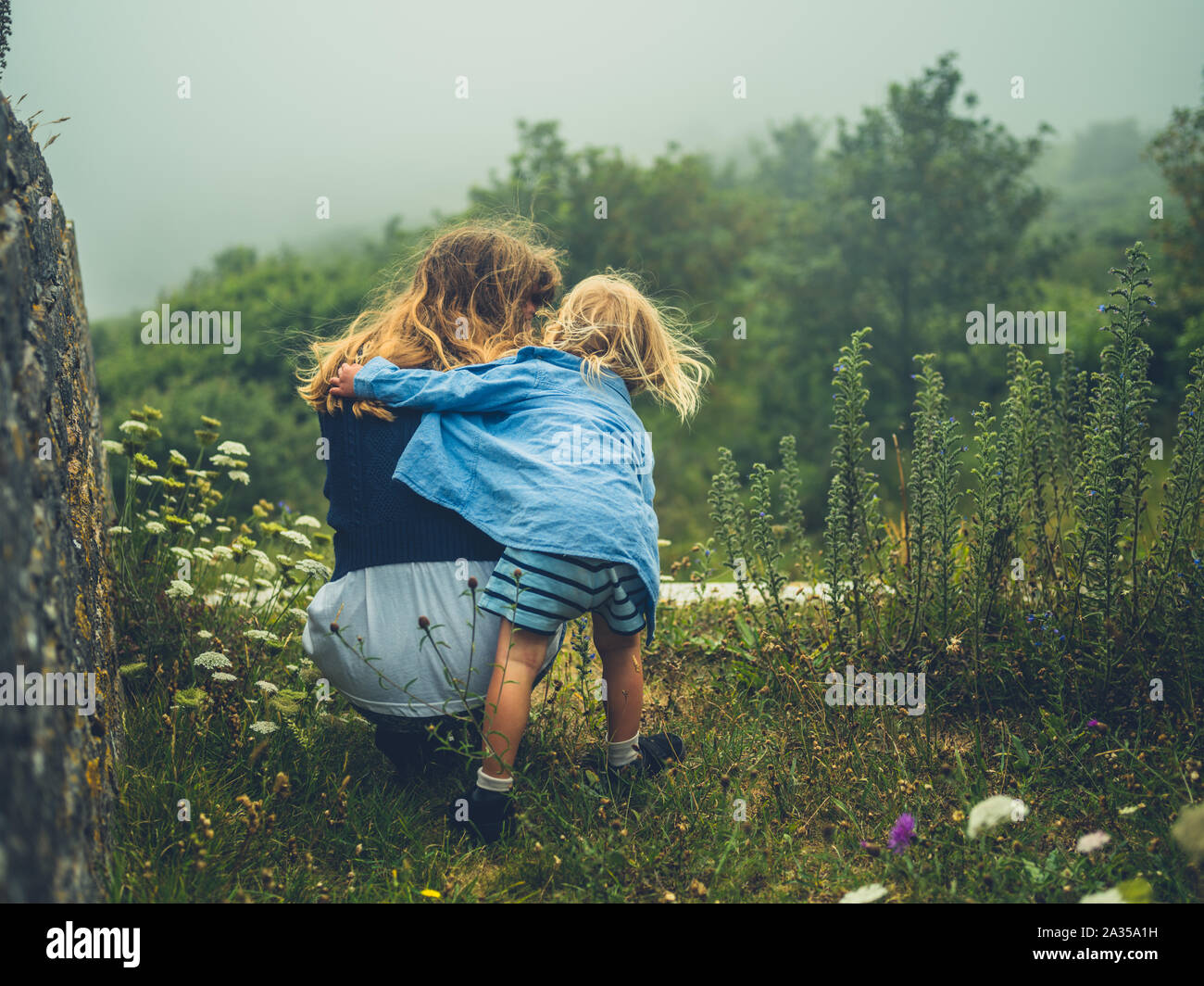 Ein kleines Kind, das seine Mutter in der Natur auf einem nebligen Tag Stockfoto