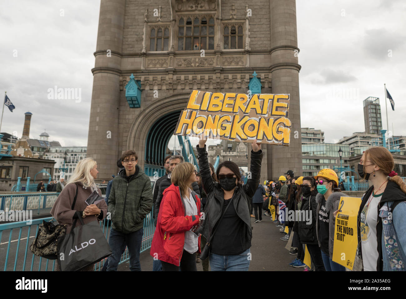 London, Großbritannien. 5. Okt, 2019. Der chinesische Künstler Badiucao und Unterstützer melden Sie die Hände in einer menschlichen Kette, eine Übersicht der Solidarität mit den Demonstranten in Hongkong. Die Lennon-mauer Flagge symbolisiert Hong Kongs Kampf für die Freiheit ist auch symbolisch angehoben. Penelope Barritt/Alamy leben Nachrichten Stockfoto