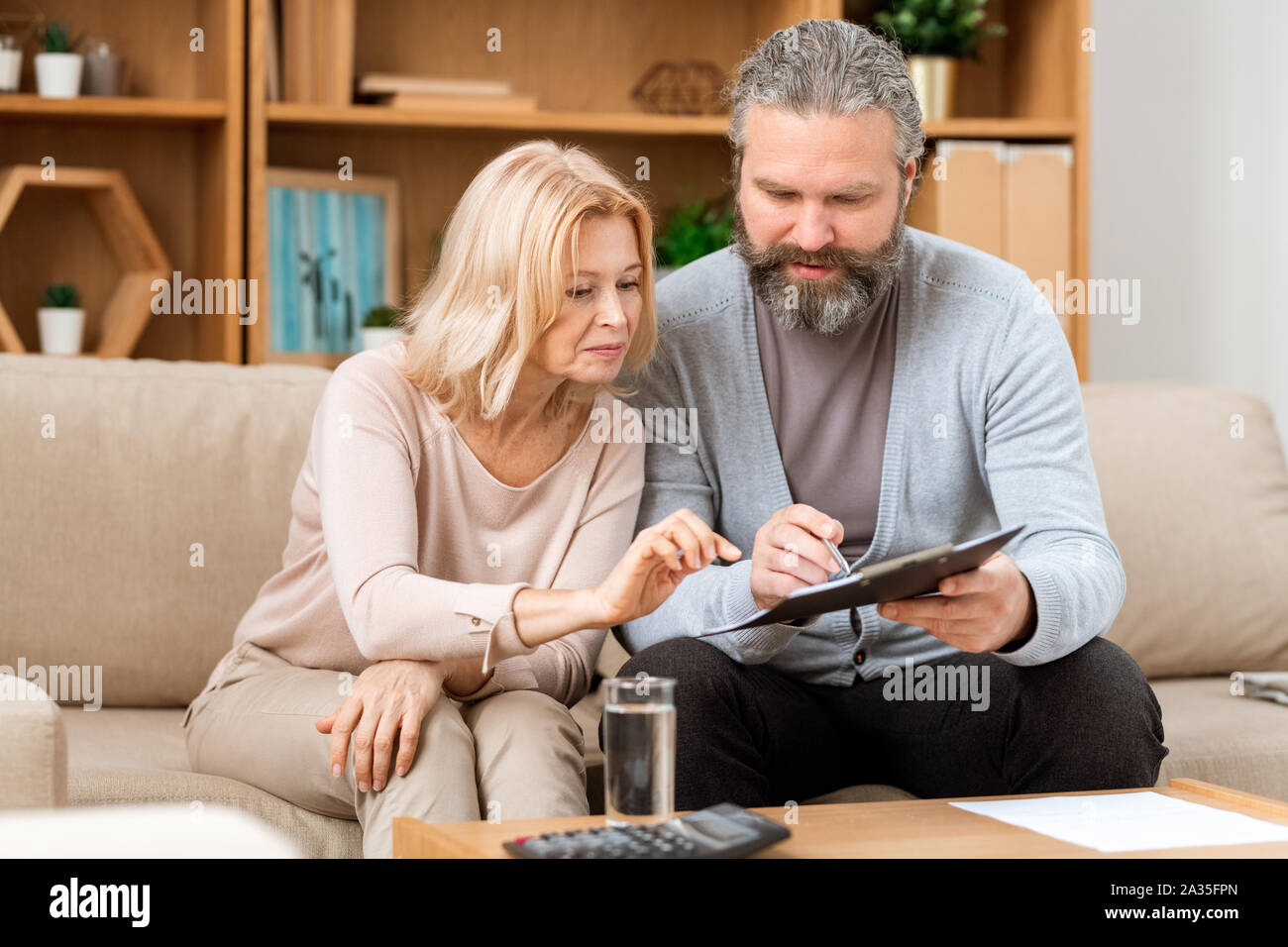 Reifer Mann und Frau Lesung Vertragsbedingungen vor Unterzeichnung Stockfoto