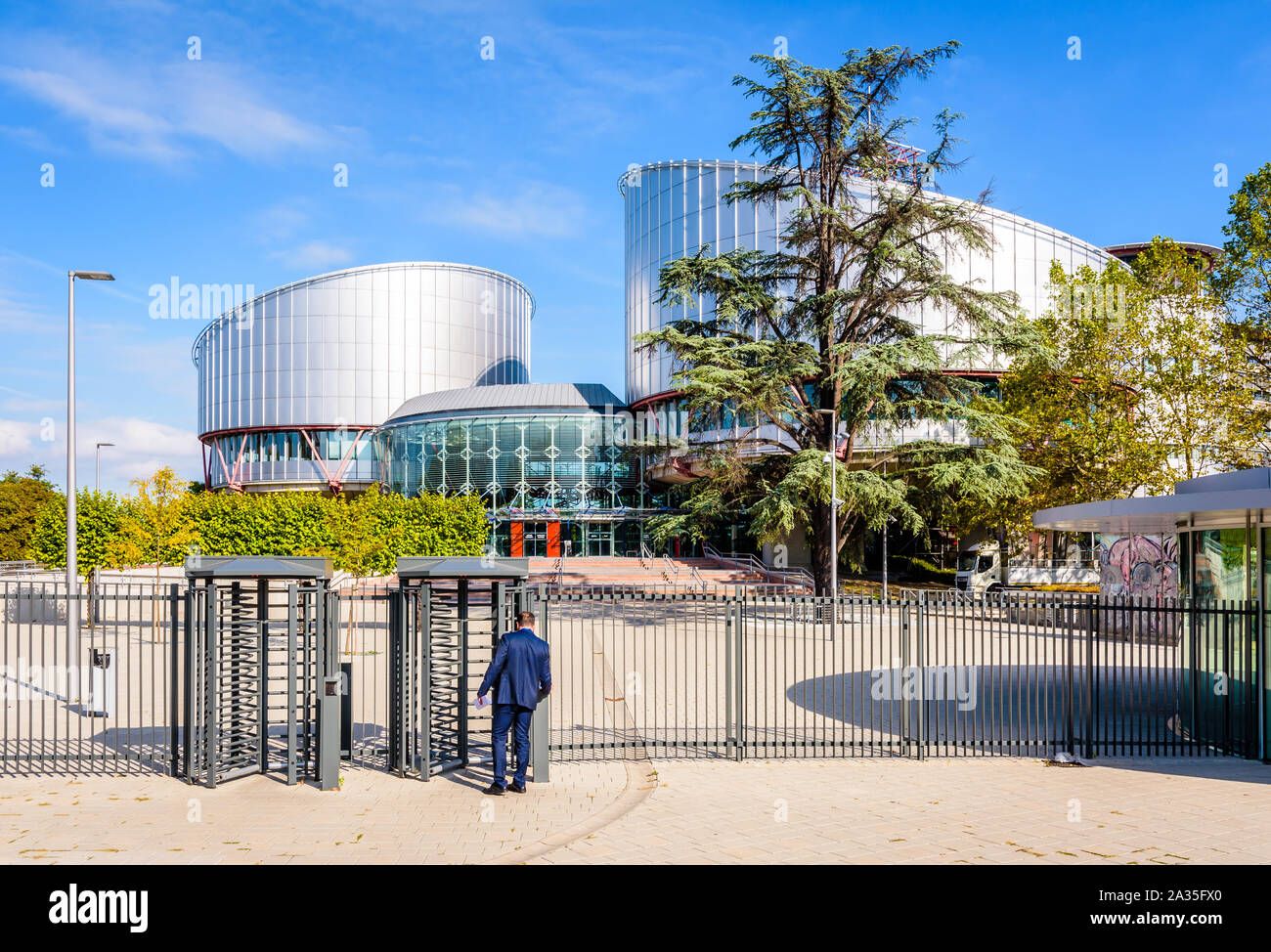 Ein Mann im blauen Anzug, das Drehkreuz der Gebäude des Europäischen Gerichtshofs für Menschenrechte in Straßburg, Frankreich. Stockfoto