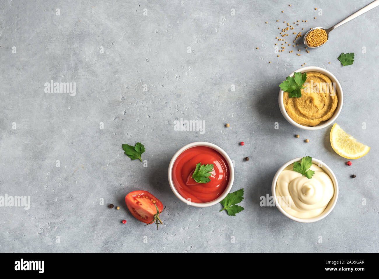 Drei klassische Saucen Ketchup, Mayonnaise und Senf auf grauem Hintergrund. Set der beliebten amerikanischen Saucen, Ansicht von oben, kopieren. Stockfoto