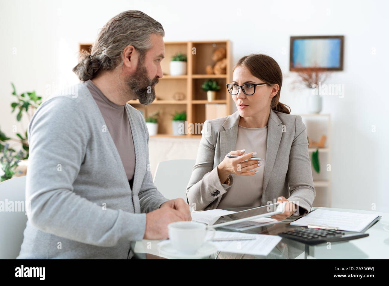 Junge real estate agent mit Touchpad Klienten hinsichtlich der Deal erklären Stockfoto