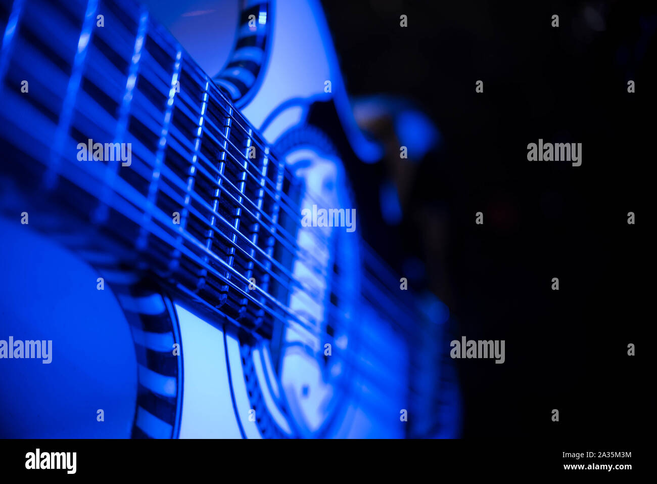 Nahaufnahme der Gitarre mit vielen Streichern und blauem Licht bei Konzert Stockfoto