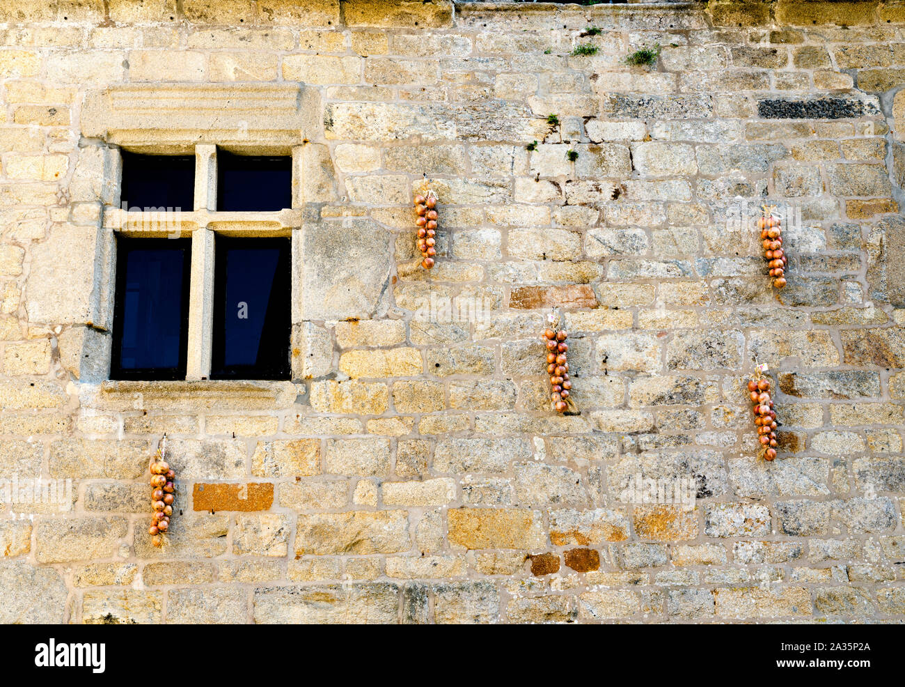 Blick auf ein altes Steinhaus Fassade in der bretonischen Dorf von Roscoff mit den typischen "Onion Johnny 'rote Zwiebel Bushel Aufhängen und Trocknen Stockfoto