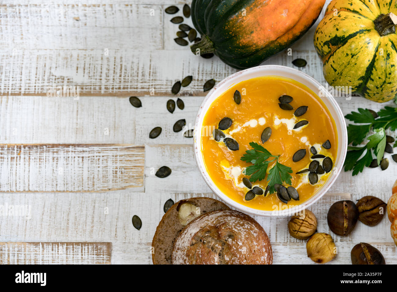 Köstliche Bio Kürbis Suppe in einer weißen Schüssel von Kastanien Kürbisse Petersilie und Kastanien Brot mit Kopie Raum gerahmte Stockfoto