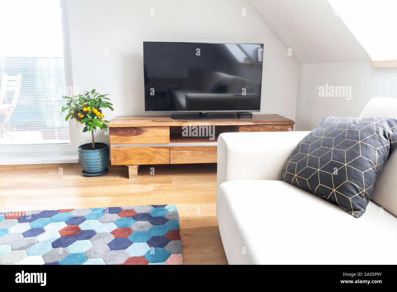 Minimalistischer Wohnzimmer mit TV-Ständer aus Holz und weißen Sofa Stockfoto