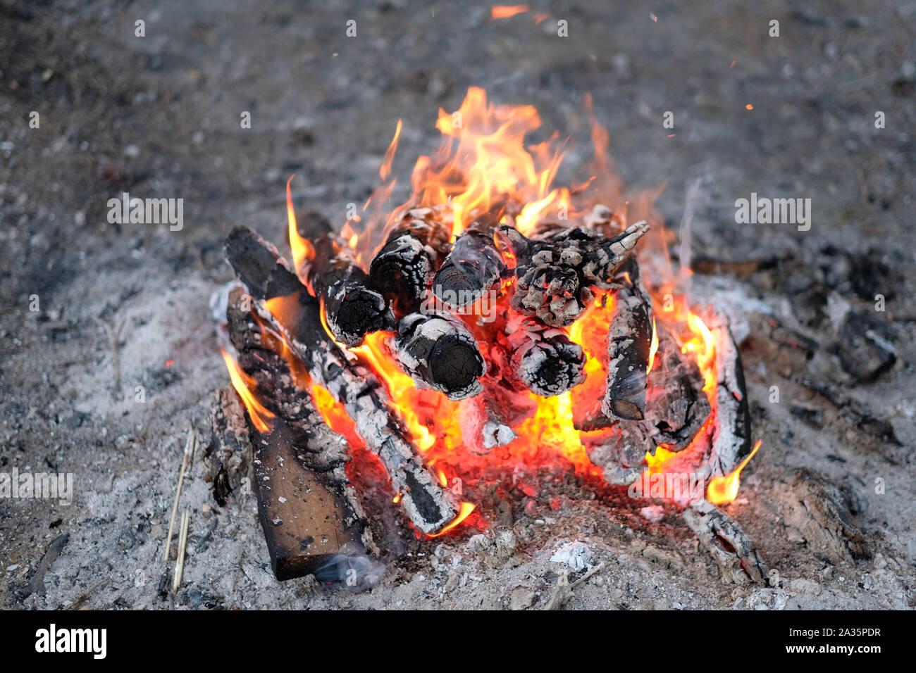 Brennen und verkohltem Holz meldet sich ein Feuer auf einem sandigen Plattform Stockfoto
