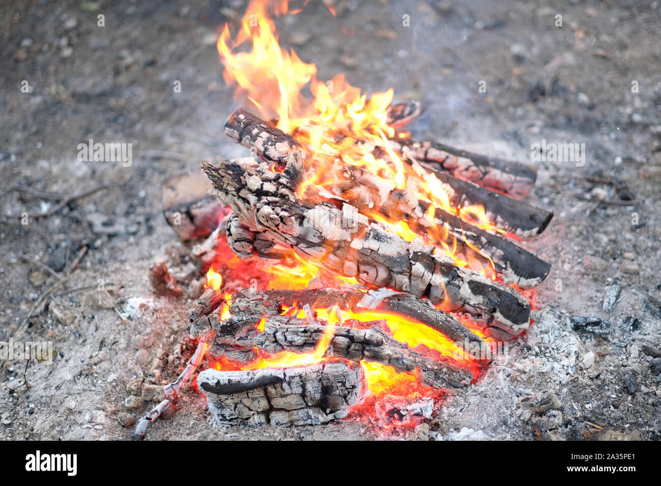 Brennen und verkohltem Holz meldet sich ein Feuer auf einem sandigen Plattform Stockfoto