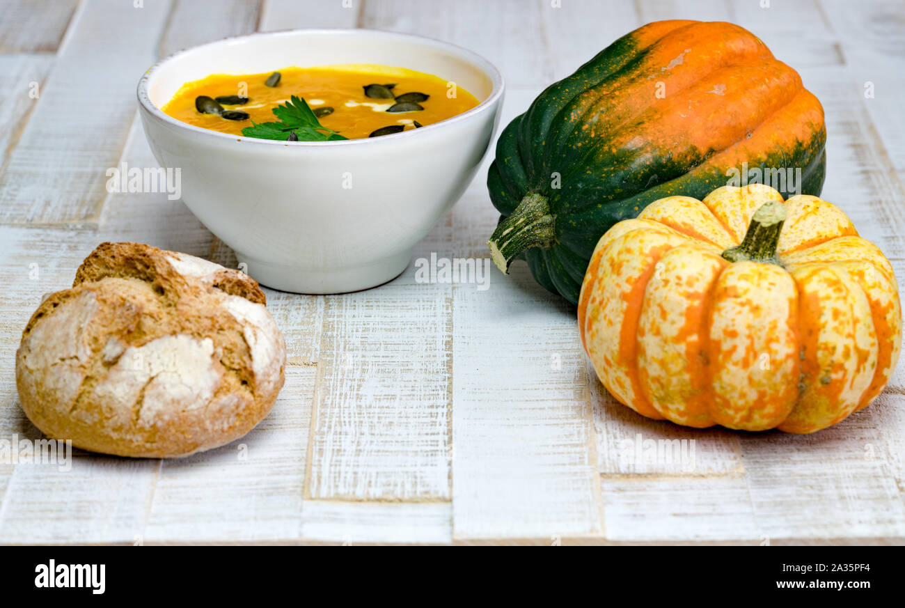 Low Angle View von organischen Kürbissuppe in einer weißen Schüssel von Kürbissen und ganze mehl brot gerahmt Stockfoto