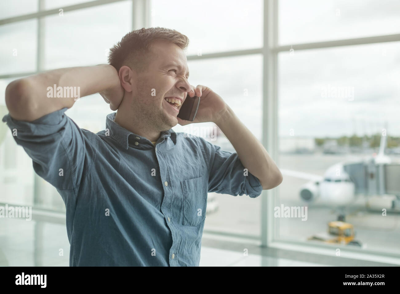 Jungen kaukasischen Mann Gespräch am Handy am Flughafen Stockfoto
