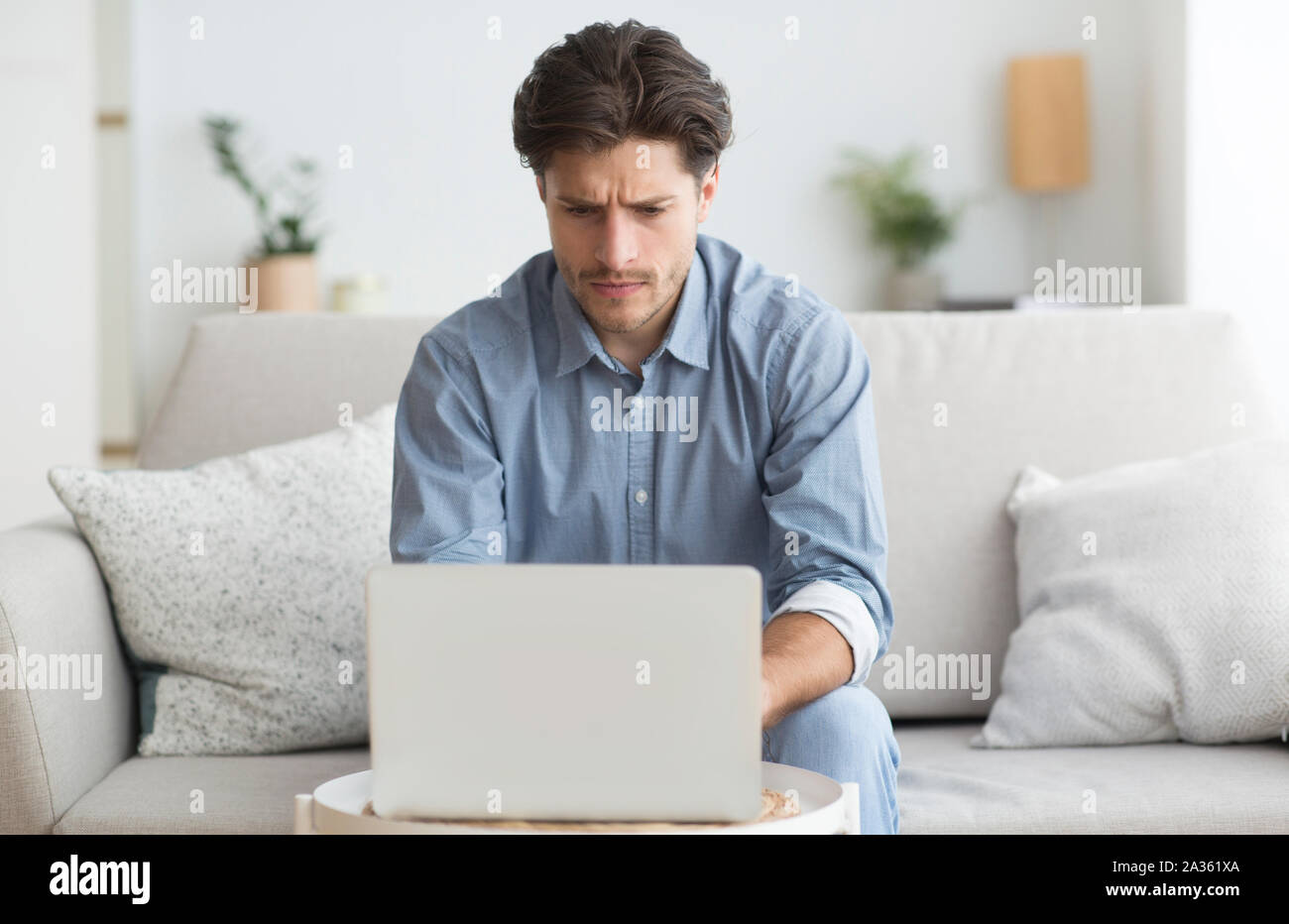 Mann bei der Arbeit am Laptop sitzen auf der Couch zu Hause Stockfoto