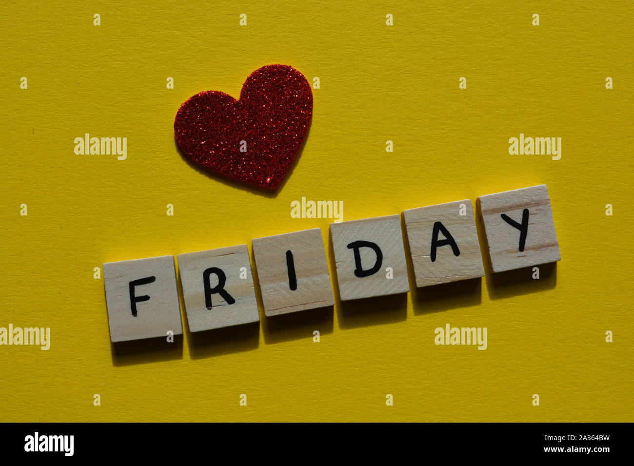 Freitag im Holz- Alphabet Buchstaben auf einem gelben Hintergrund mit rotem Glitter Herz Stockfoto