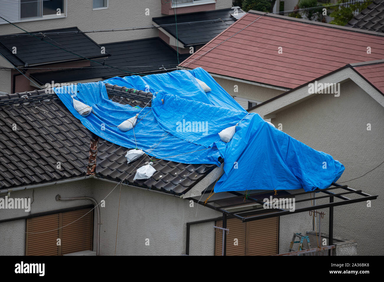 Tattered blaue Plane auf dem Dach nach starken Taifun wind Beschädigungen Stockfoto