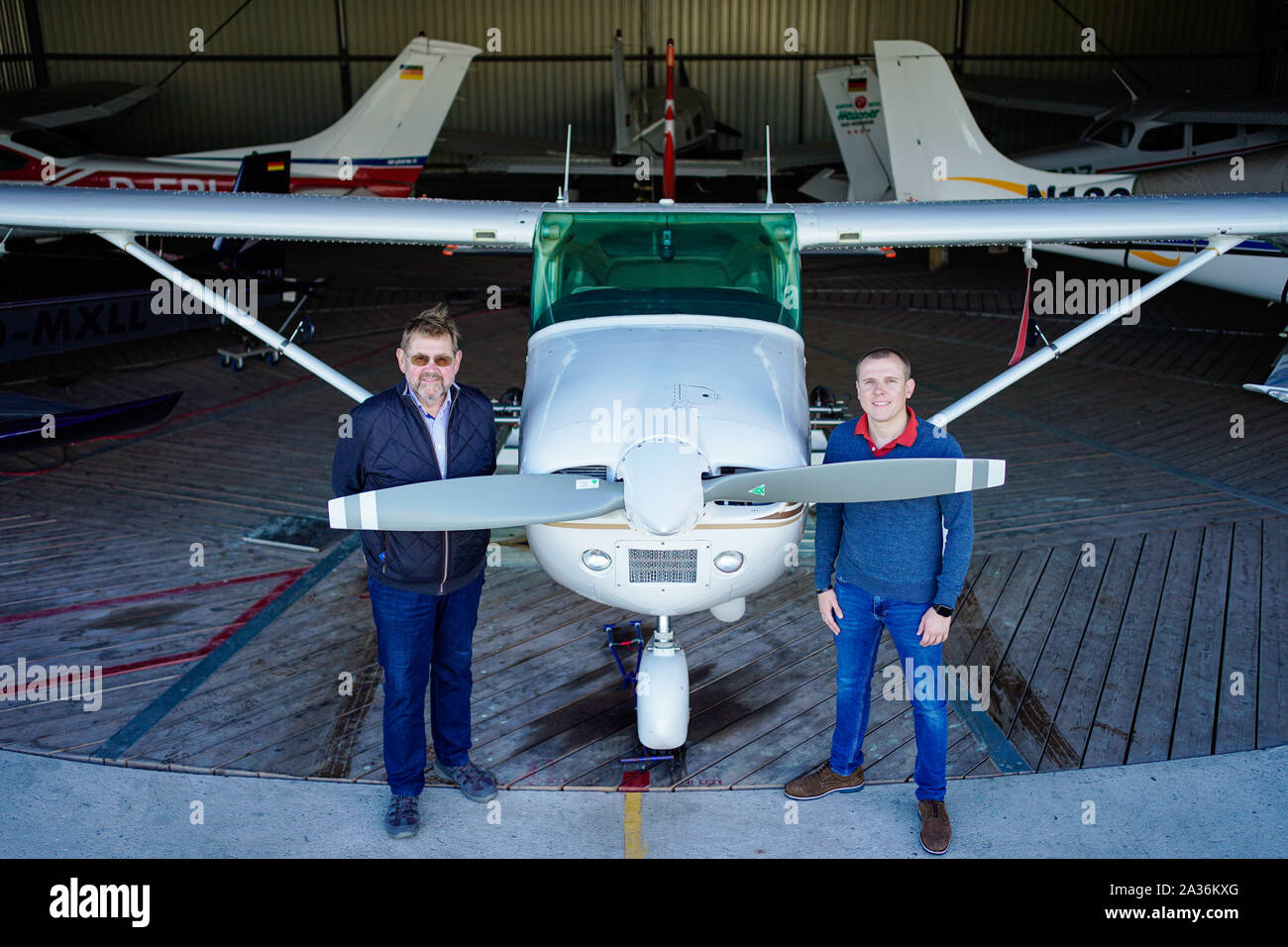 30. September 2019, Rheinland-Pfalz, Bad Dürkheim: Die Piloten Otto-Wilhelm (l) und Marc Umstätter stehen auf dem Flugplatz bei einem Cessna 182 in einem Hagel plane (dpa ''Wackeln tuts immer': Besuchen Sie das schlechte Wetter Piloten der Pfalz") umgewandelt. Foto: Uwe Anspach/dpa Stockfoto