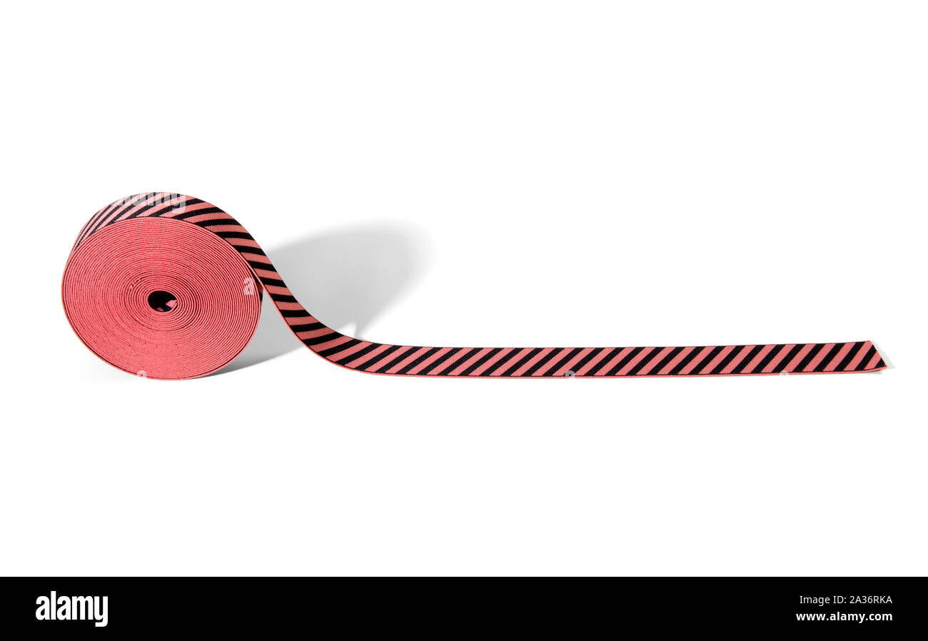 Rolle mit bunt gestreiften roten und schwarzen elastische Band auf Rand auf weißem Hintergrund mit Kopie Raum angezeigt, für den Einsatz in der Fertigung in der Mode Stockfoto