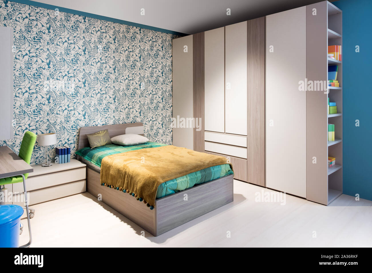 Blau und Grün themed Schlafzimmer Innenraum mit Wand Papier, Holz- Schränke und ein einzelschlafdivan neben einem kleinen Schreibtisch Stockfoto