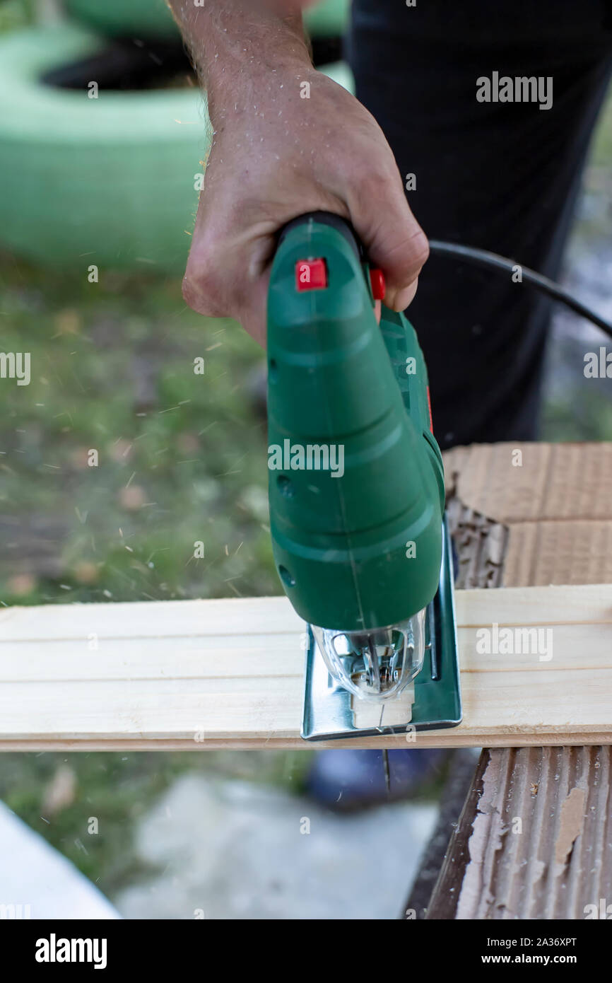 Mann schneidet Holz Produkte, verwenden elektrische Stichsägen im Freien. Close-up. Stockfoto