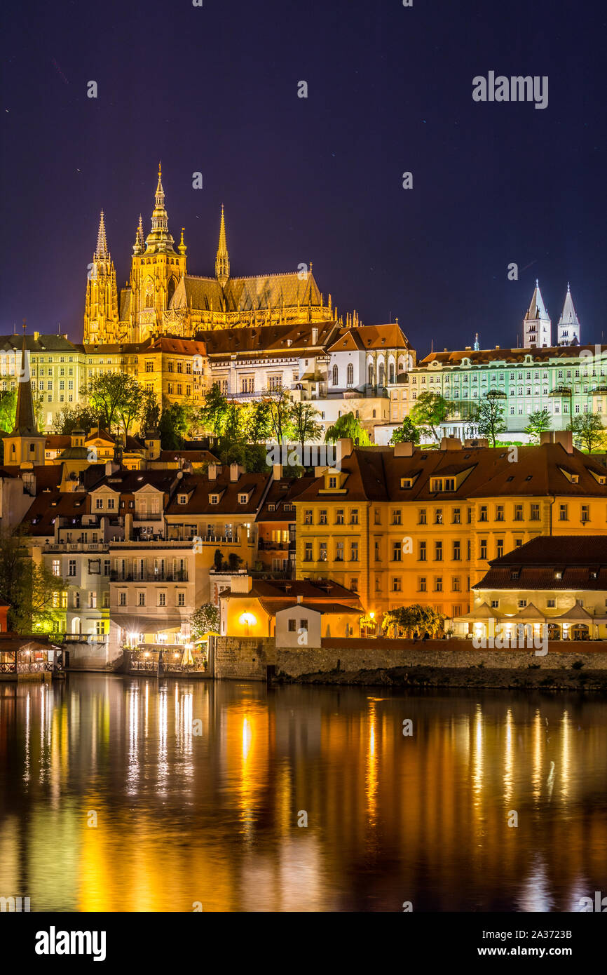 Nacht Blick auf die Prager Burg, das grösste zusammenhängende Burganlage in der Welt, mit der Reflexion über die Moldau. Stockfoto