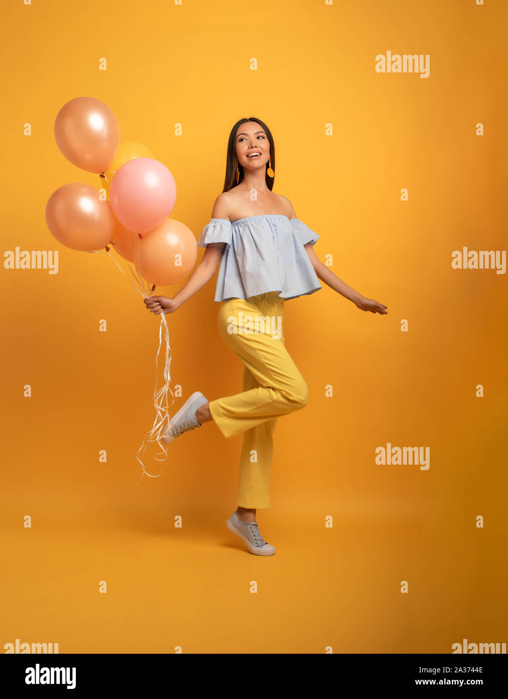 Mädchen bereit für eine Party mit Ballon. Freudige ein Glück Ausdruck. Gelber Hintergrund Stockfoto