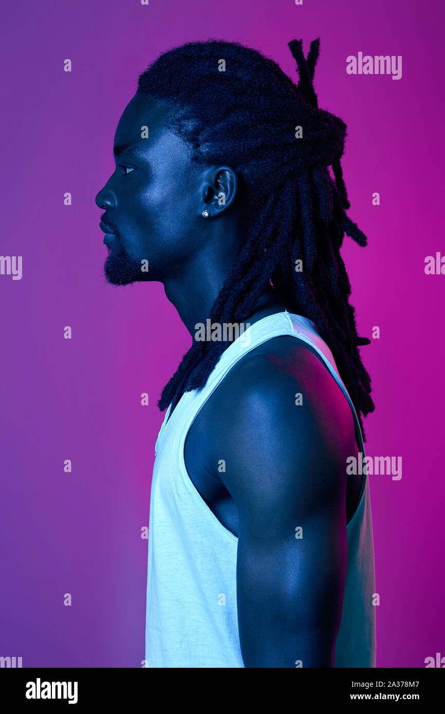 Profil von stattlichen Afro Kerl mit stilvollen Dreads, Nahaufnahme, Seite, Ansicht Portrait, stilvolle und Fashion Concept. rosa isoliert und violette Hintergrund Stockfoto