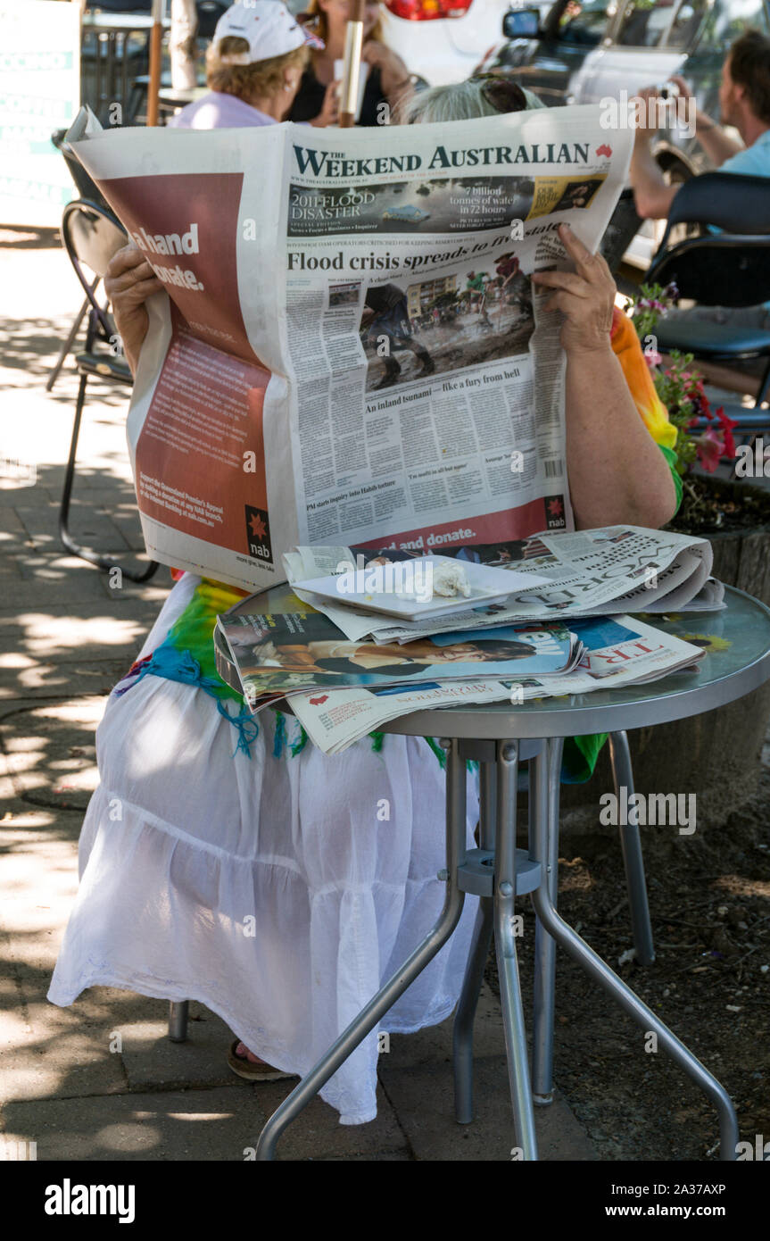 Eine Frau, die in der Hauptstraße der alten deutschen Pionierstadt Hahndorf in den Adelaide Hills, etwa 25 km von der Stadt entfernt, eine australische Zeitung liest Stockfoto