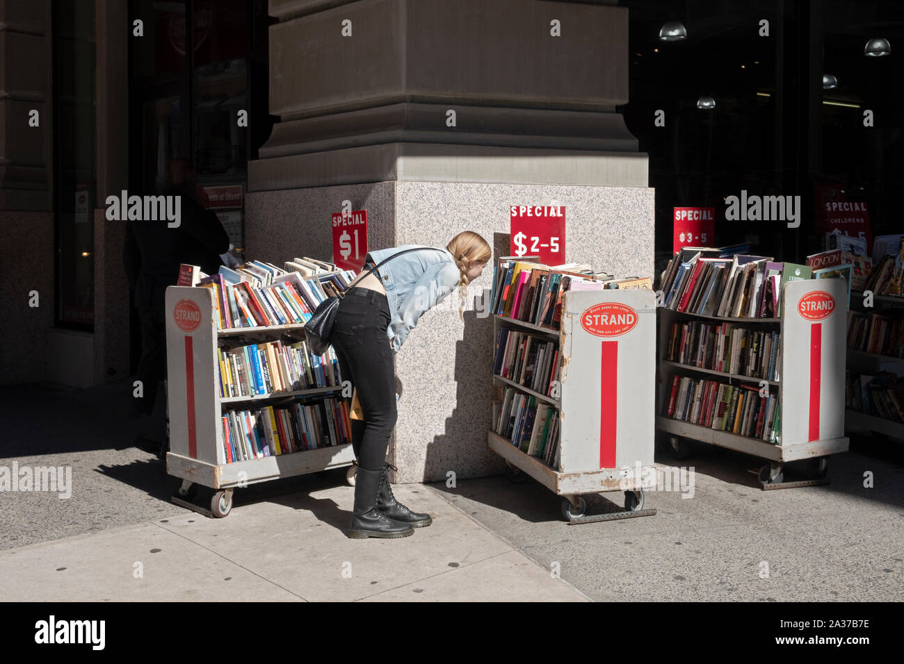 Eine junge Dame sucht die Bücher auf den Verkauf außerhalb der Faser Buchhandlung am Broadway in Greenwich Village, Manhattan, New York City. Stockfoto