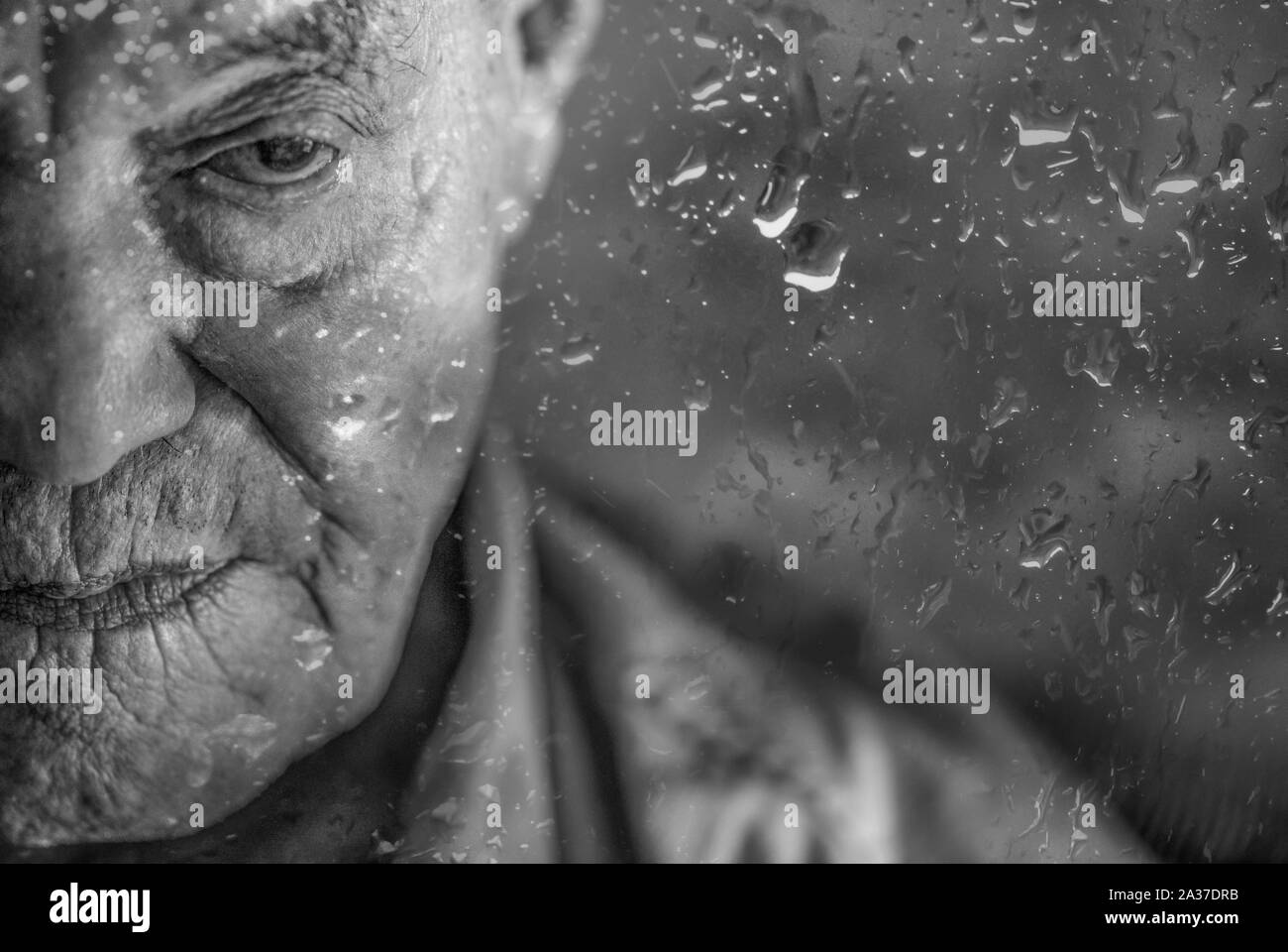 Paranaguá, Paraná, Brasilien - 18. November 2015: Brasilianische älterer Mann mit Blindheit hinter einem Fenster mit Regen fällt, nachdenklich Stockfoto