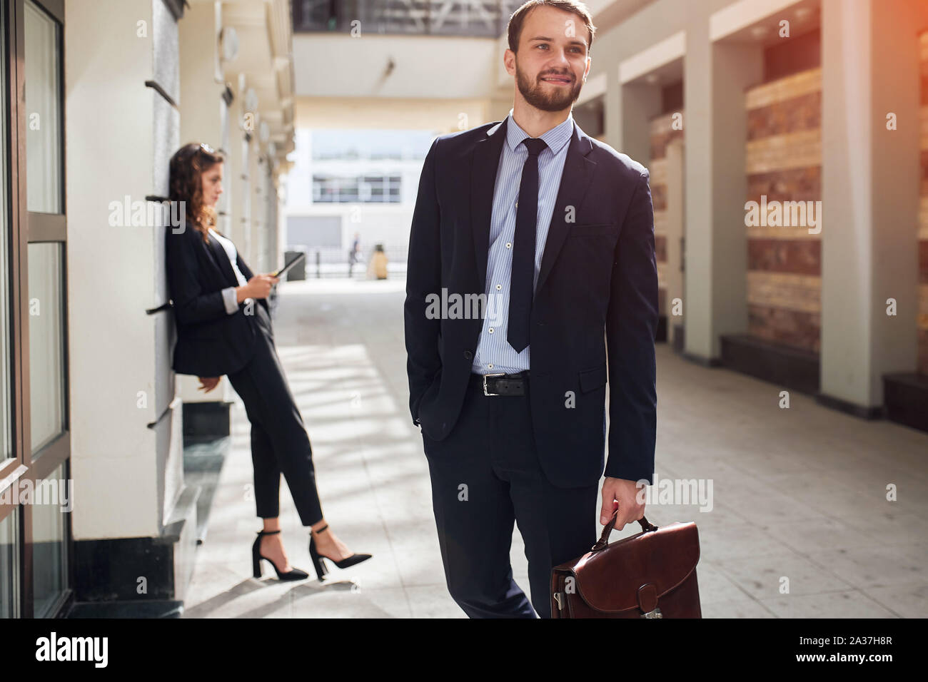 Gerne ambitionierter Geschäftsmann aus dem Bürogebäude, elegante Frau im eleganten Anzug mit einer Tablette lehnte sich an die Wand. nach oben schließen Foto Stockfoto