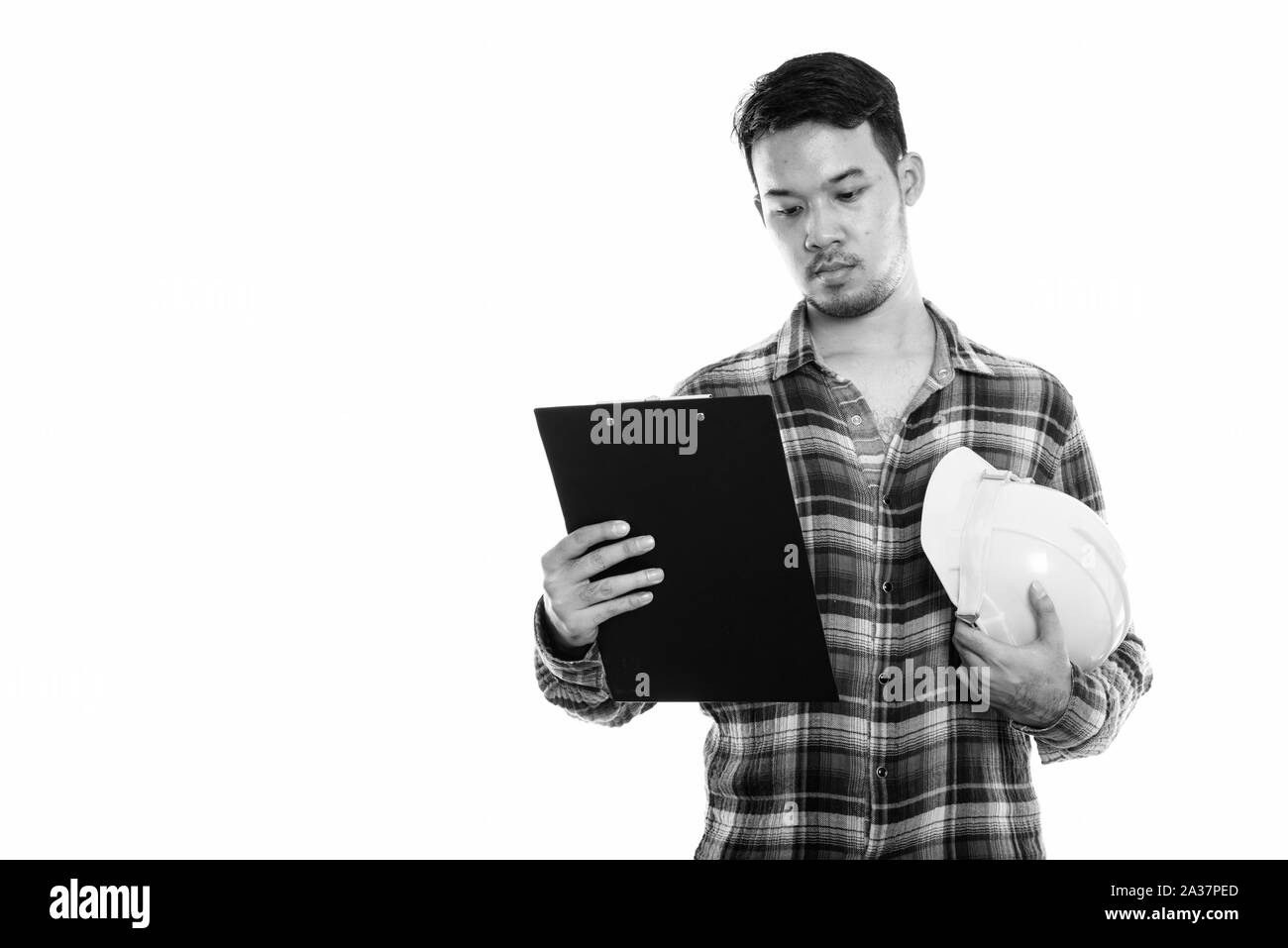 Studio shot junger asiatischer Mann Bauarbeiter Lesung am Klemmbrett mit holding Schutzhelm Stockfoto