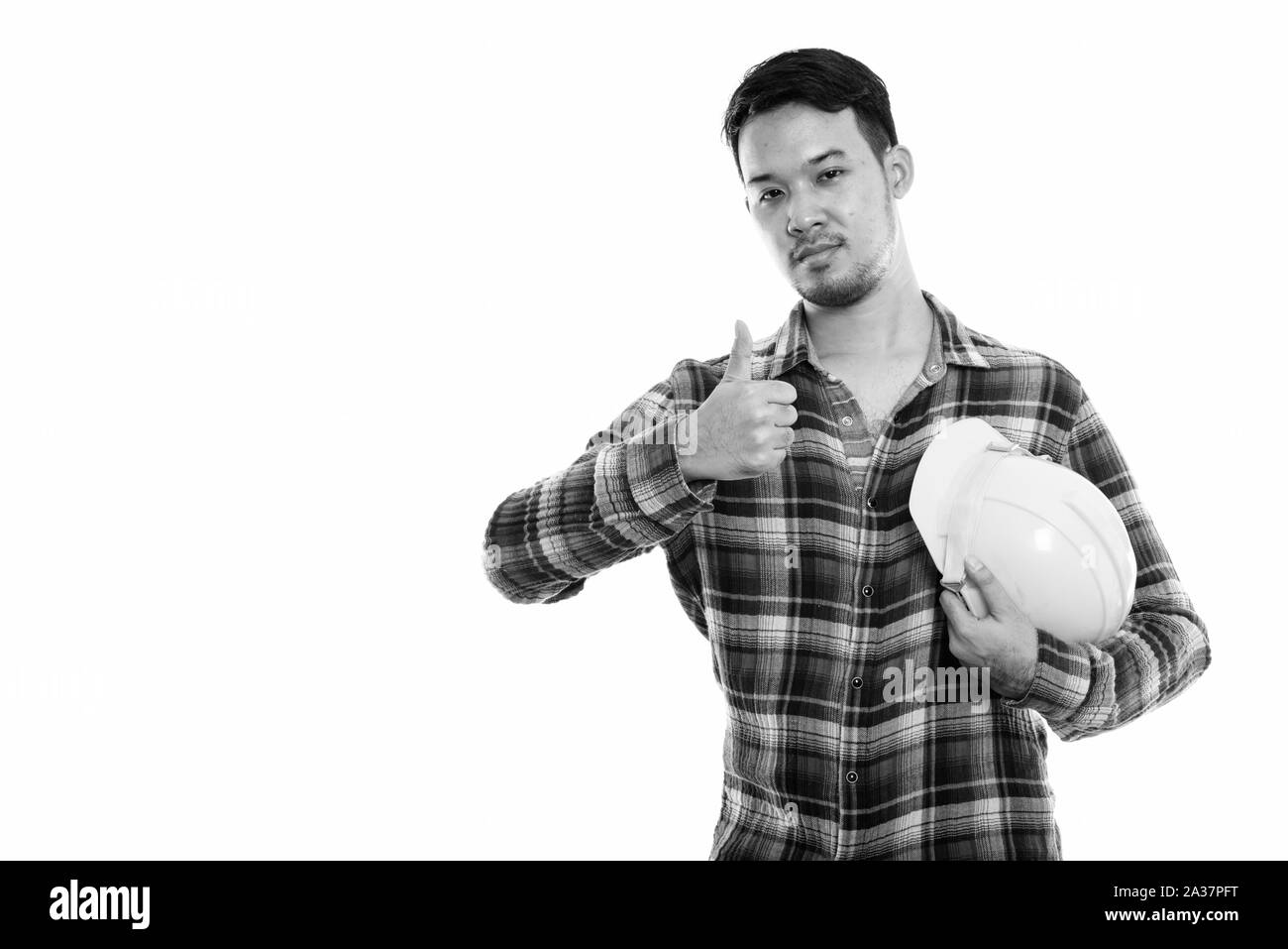 Studio shot junger asiatischer Mann Bauarbeiter holding Schutzhelm beim Geben Daumen hoch Stockfoto