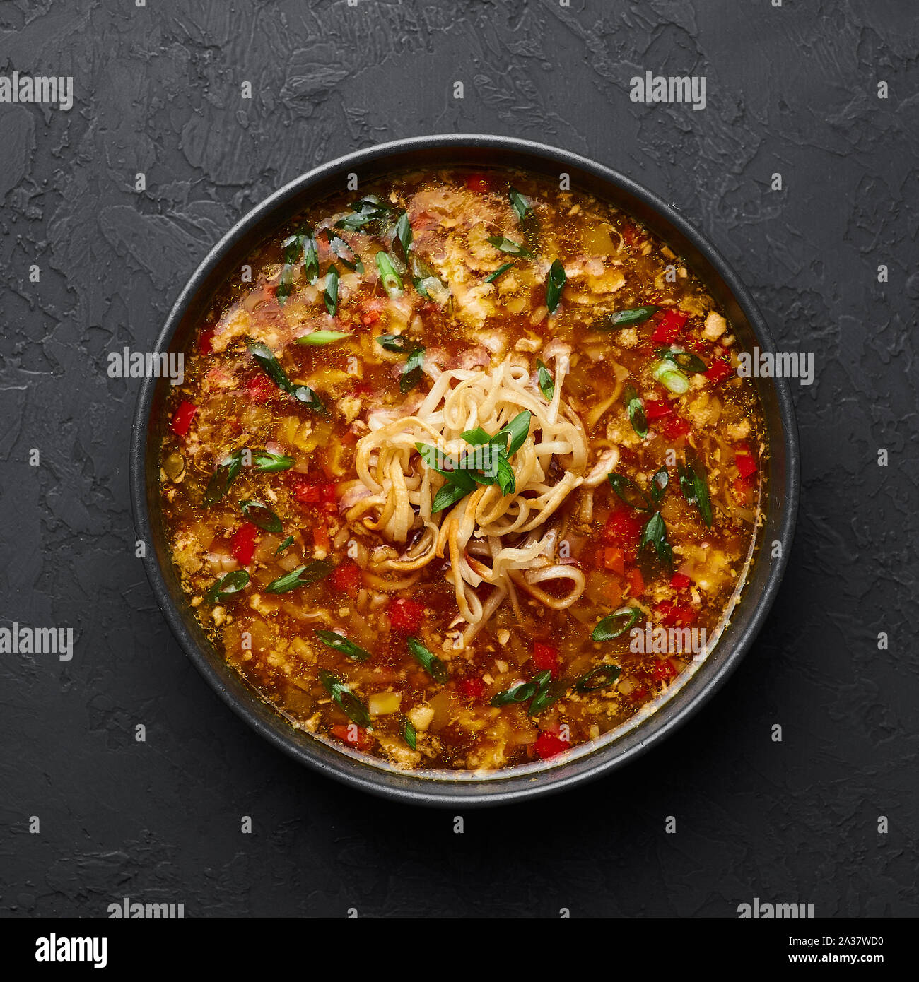 Veg Manchow Suppe in schwarz Schüssel am dunklen Schiefer Hintergrund. Vegetarische Manchow Suppe ist indo-chinesischen Küche Teller mit Paprika, Kohl, Karotten, nood Stockfoto