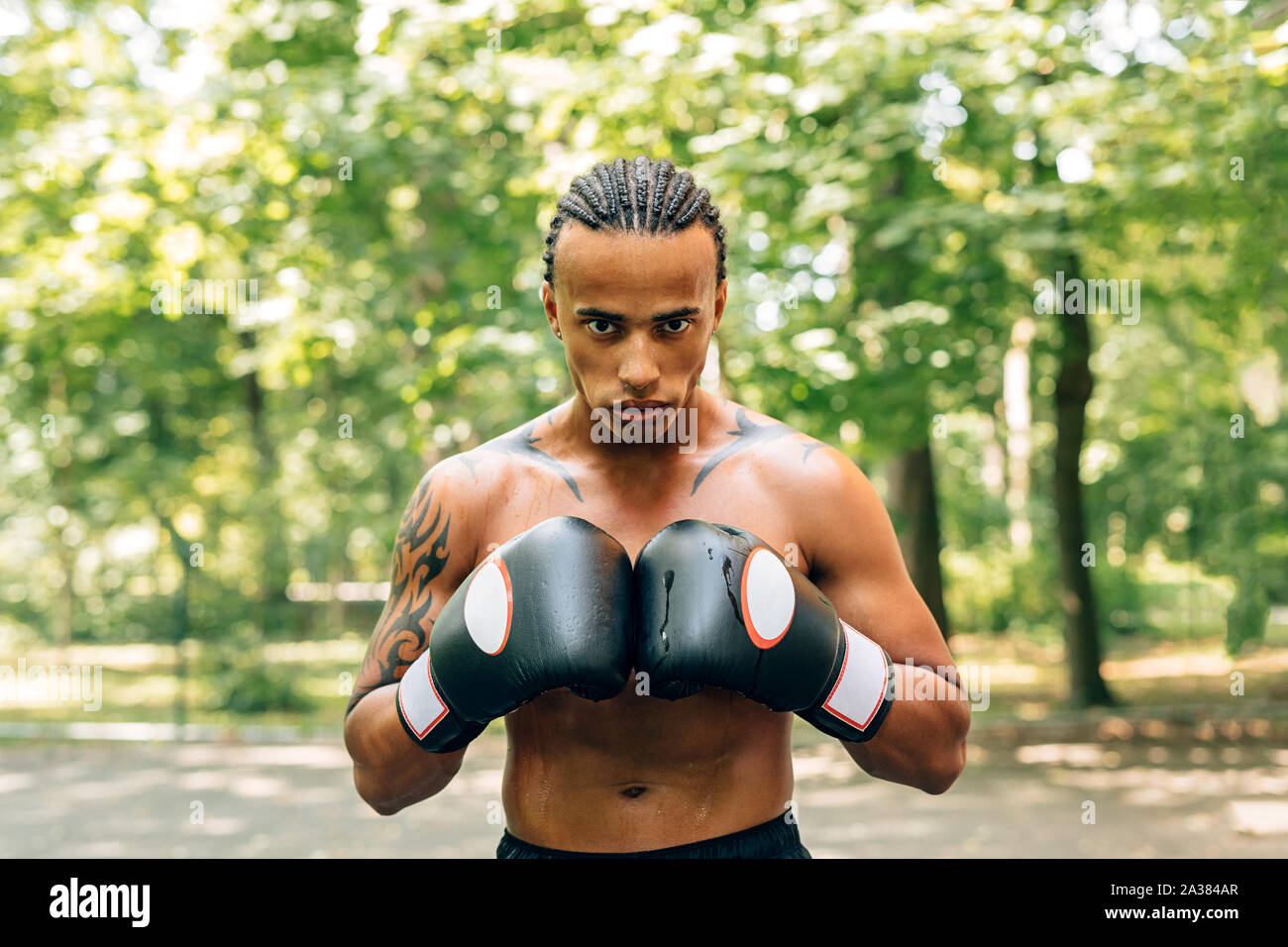 Porträt einer geschwitzt männliche Boxer mit Handschuhen und Mundschutz stehen draußen auf dem Sportplatz Stockfoto