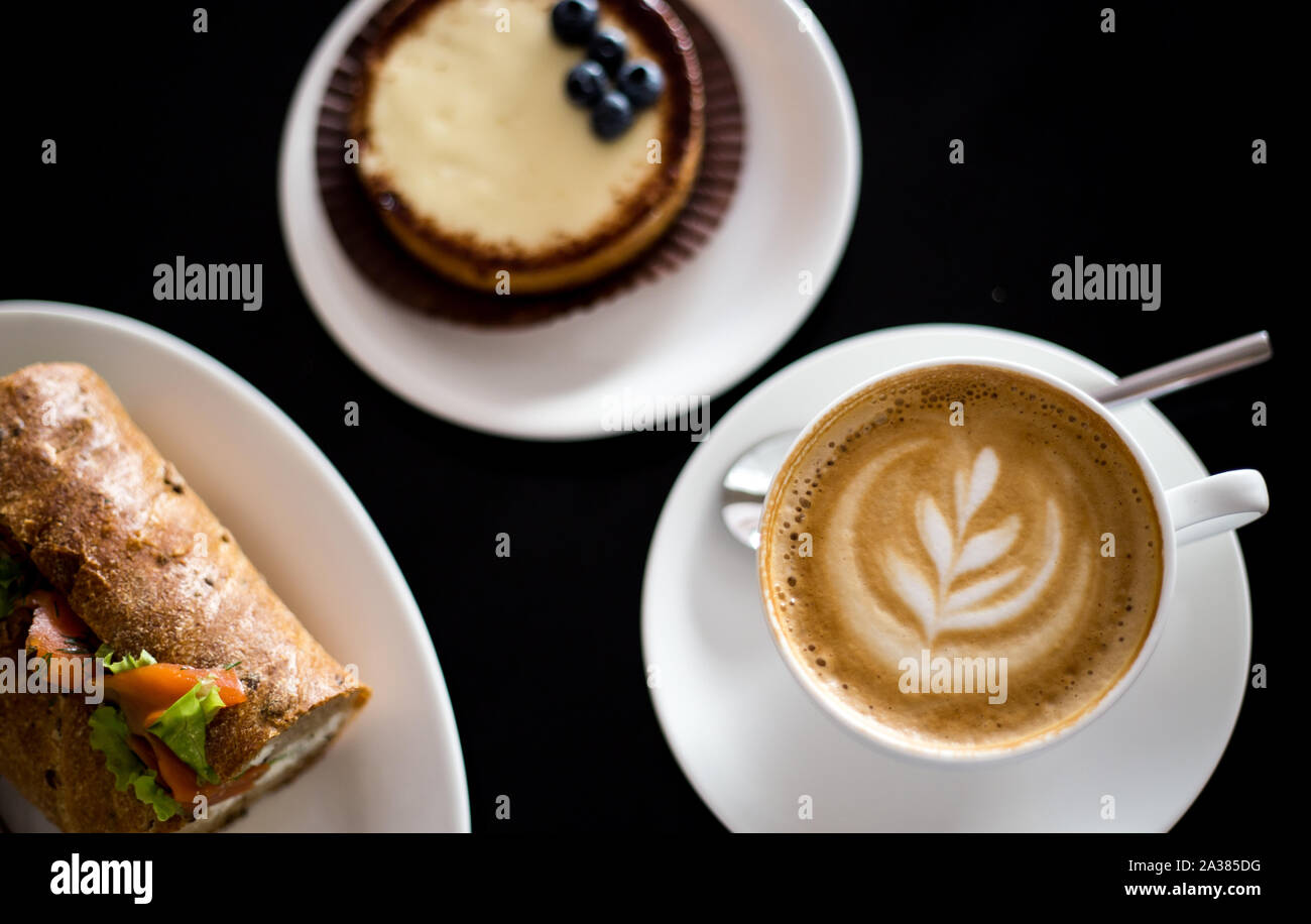 Frühstück mit Cappuccino mit Kaffee Kunst und Lachs Sandwich Stockfoto