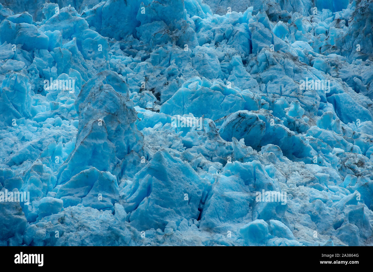 Große Eisblöcke des nordwestlichen Gletschers, intensiv blau gefärbt, teilweise dünn mit Staub bedeckt, an einem bewölkten Sommertag. Stockfoto