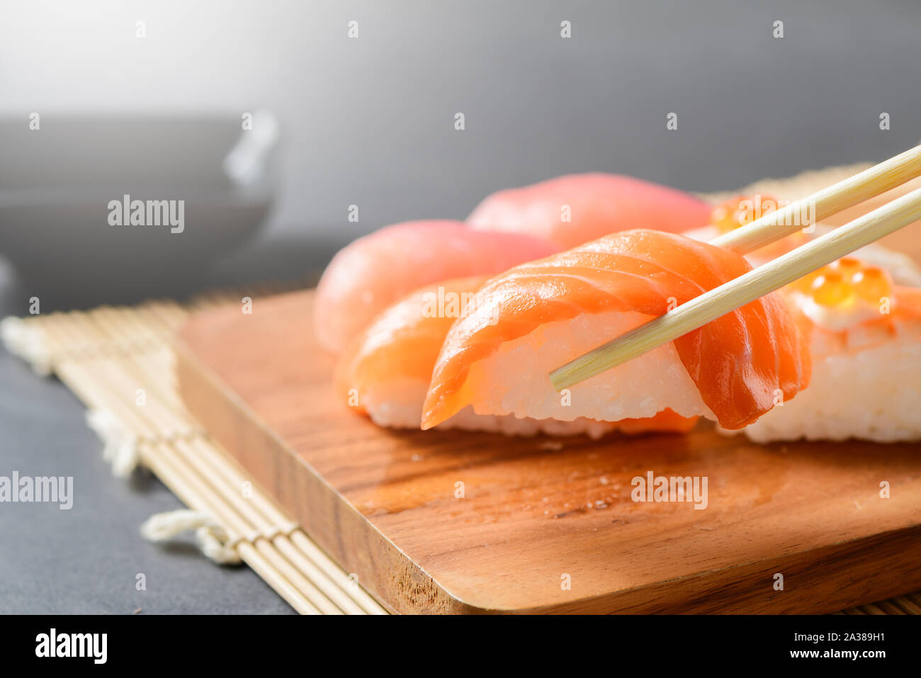 Lachs nigiri Sushi mit Stäbchen mit Sashimi Sushi am Schwarzen Stein Hintergrund gesetzt, japanische Küche Stockfoto