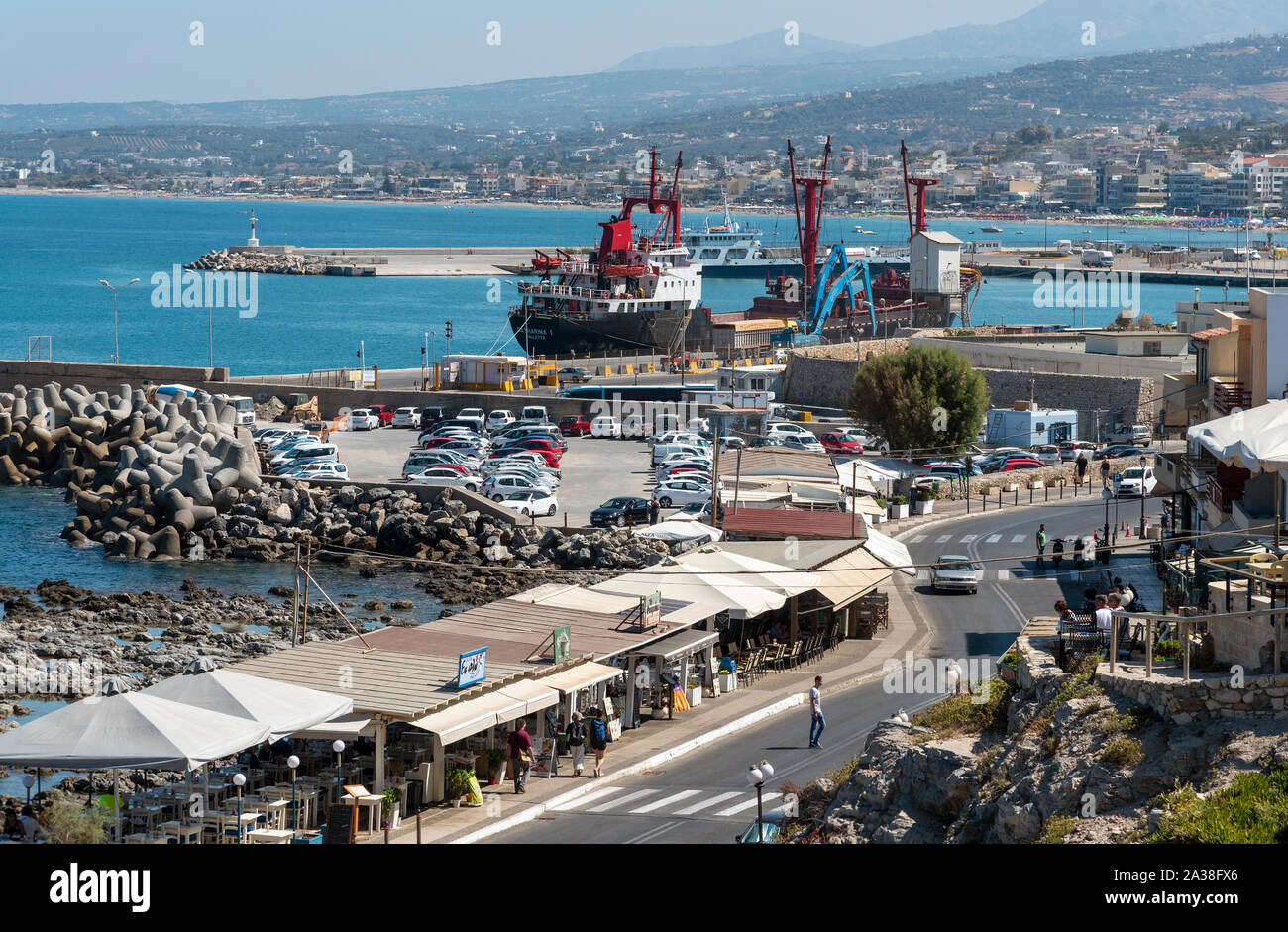 Rethymno, Kreta, Griechenland. September 2019. Frachtschiffe am Kai in diesem kleinen kretischen Port. Parkplatz und Waterfront Restaurants Stockfoto