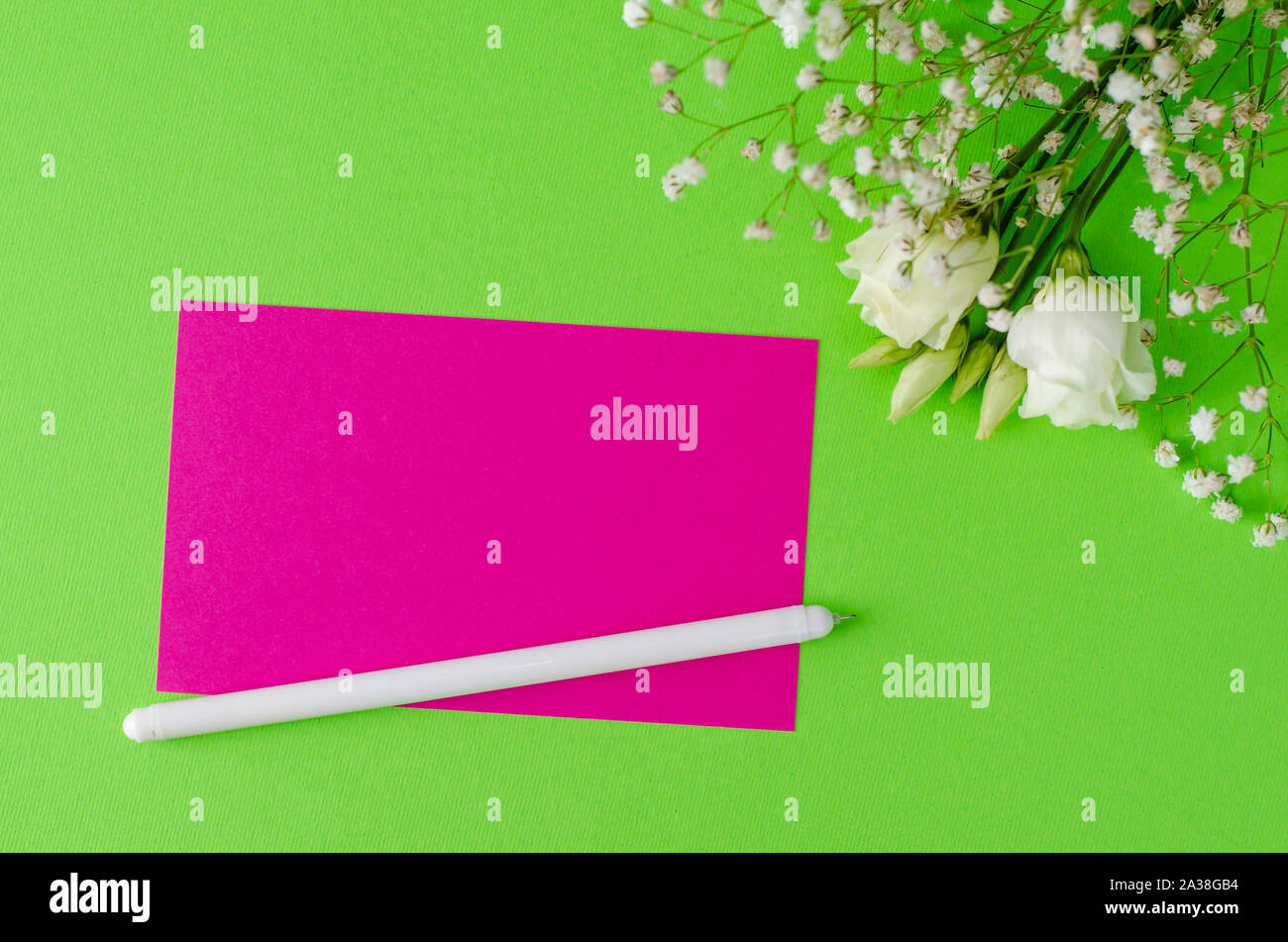 Minimalistische Komposition mit Rosa leere Karte, Stift und Blumen auf grünem Hintergrund. Flay legen, mockup Konzept. Platz für Text Stockfoto