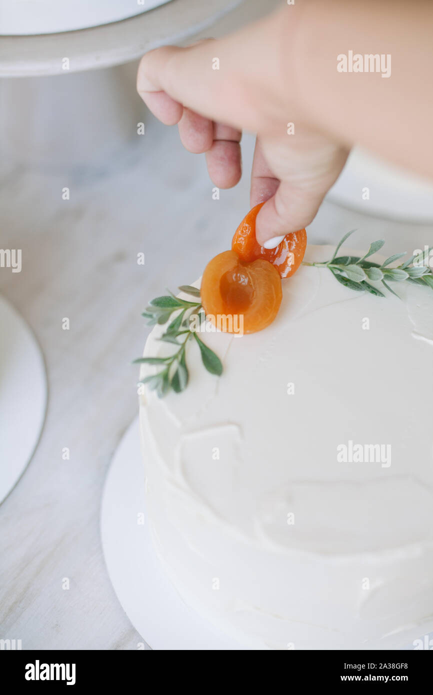 Frau Dekorieren ein Kuchen mit Pfirsichen und Blätter Stockfoto