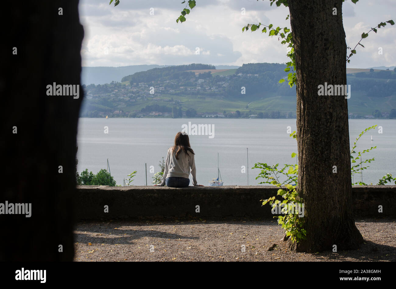 Junges Mädchen sitzt an einem See in Aussicht suchen, Schweiz Stockfoto