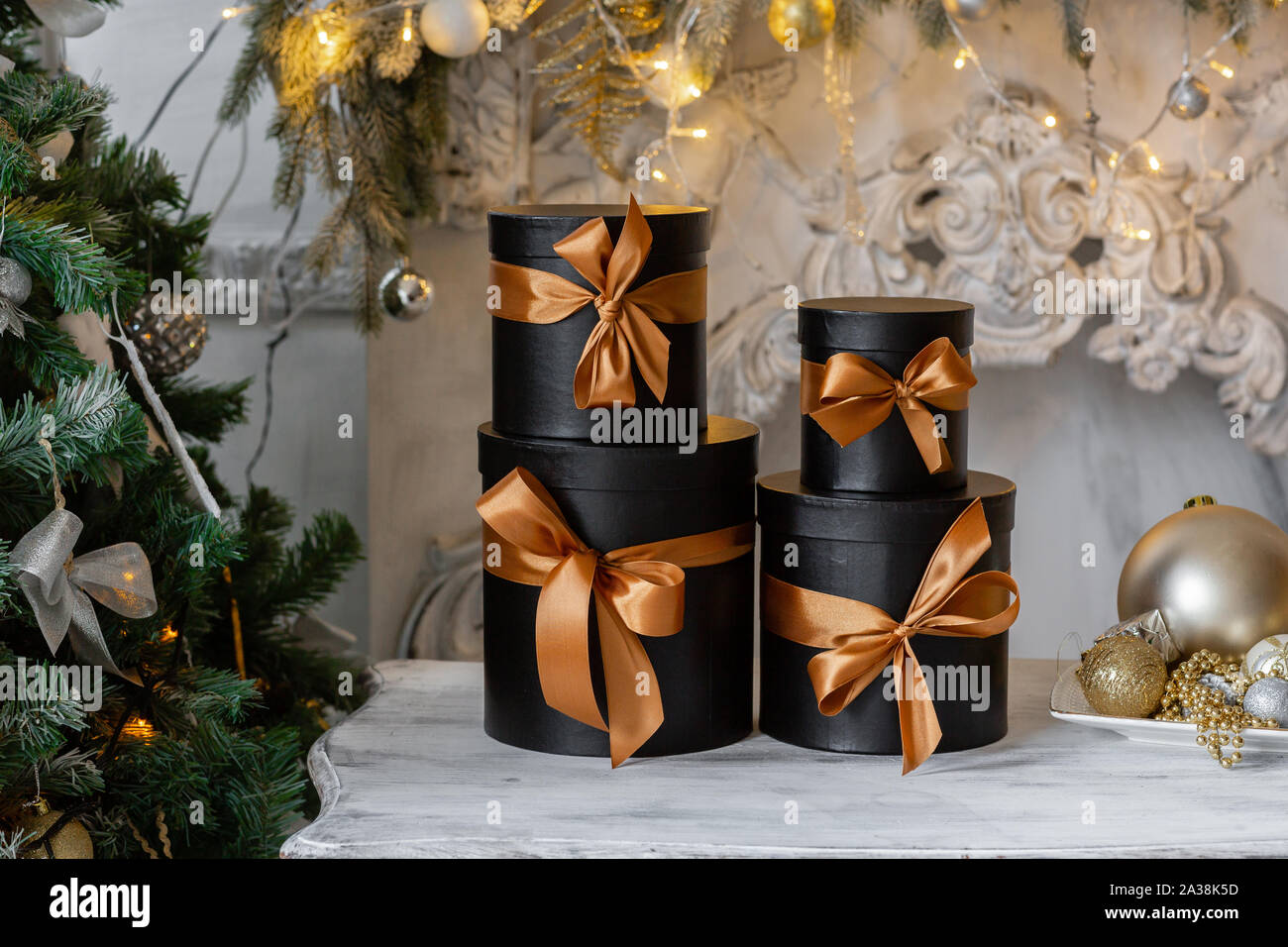Schwarze Kästen mit Bändern als Weihnachtsgeschenke auf einem Tisch Luxus weiße Wand design bas-relief Stuckverzierungen Stockfoto