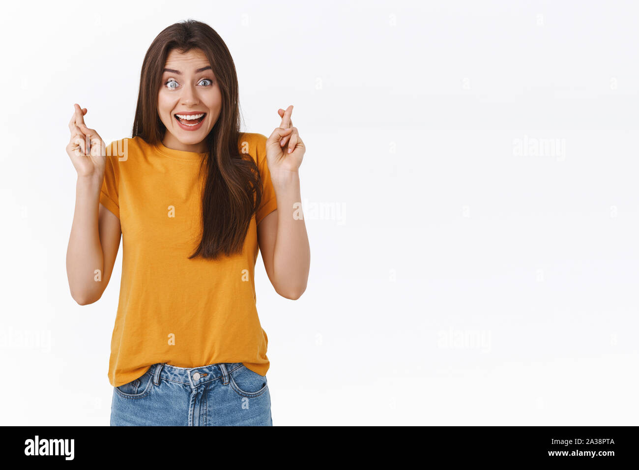 Begeistert, aufgeregt, attraktive Frau im gelben T-Shirt, halten Sie die Finger gekreuzt und lächelnd mit Erwartung in den Augen, glauben, dass Träume wahr werden, so dass Stockfoto