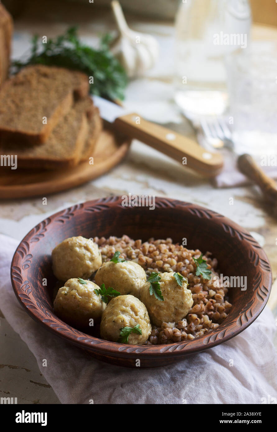 Fleischbällchen in saurer Sahne-Sauce, serviert mit Buchweizenbrei, Brot und Knoblauch. Rustikaler Stil. Stockfoto