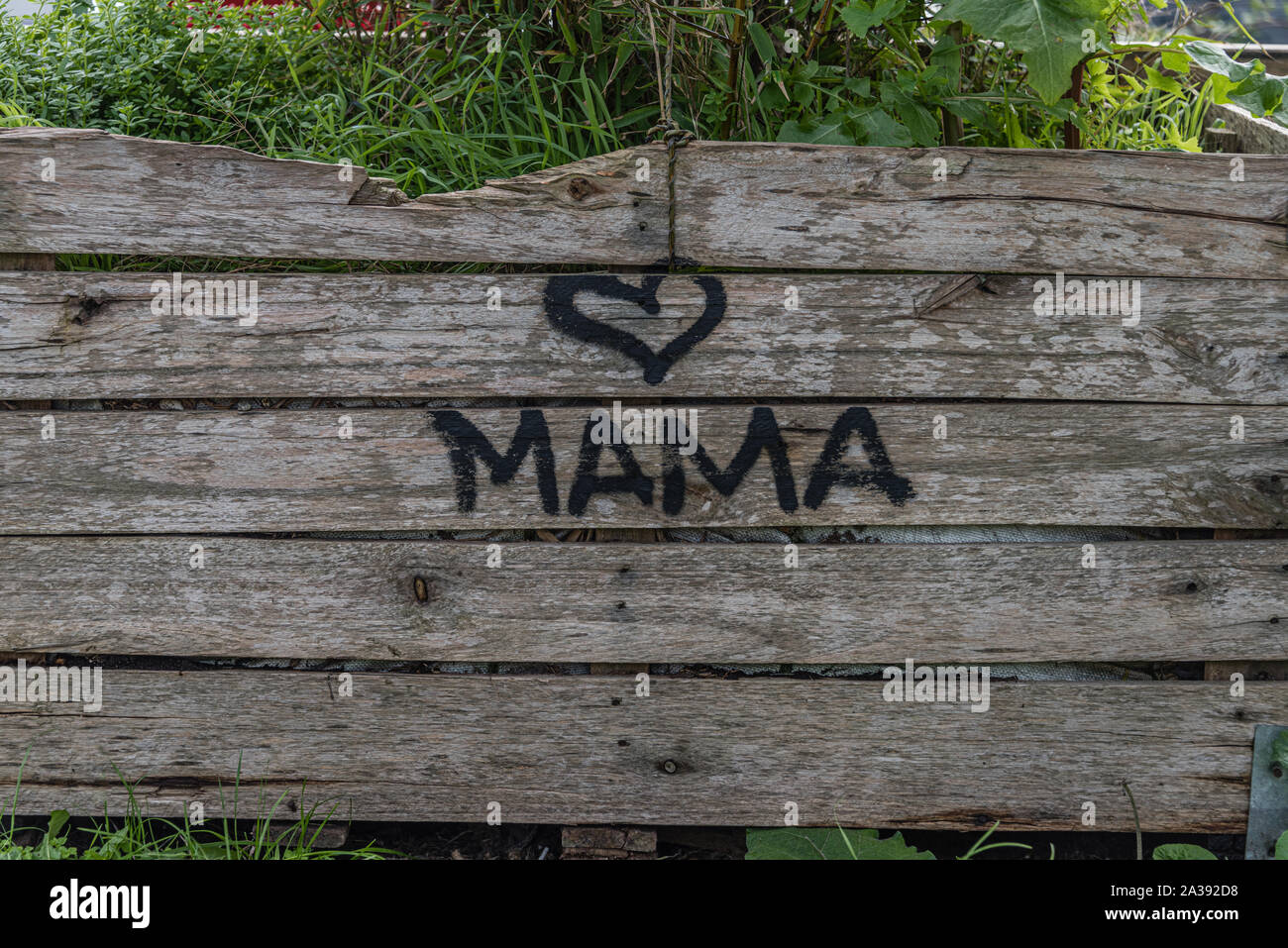 Ich liebe Mama mit Herz auf Holzbohlen mit etwas Gras auf geschrieben Stockfoto
