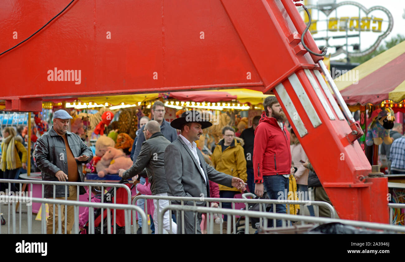Dapper Mann mit großem Hut, bei Goose Fair durch große hydraulische Arm gerahmt Stockfoto