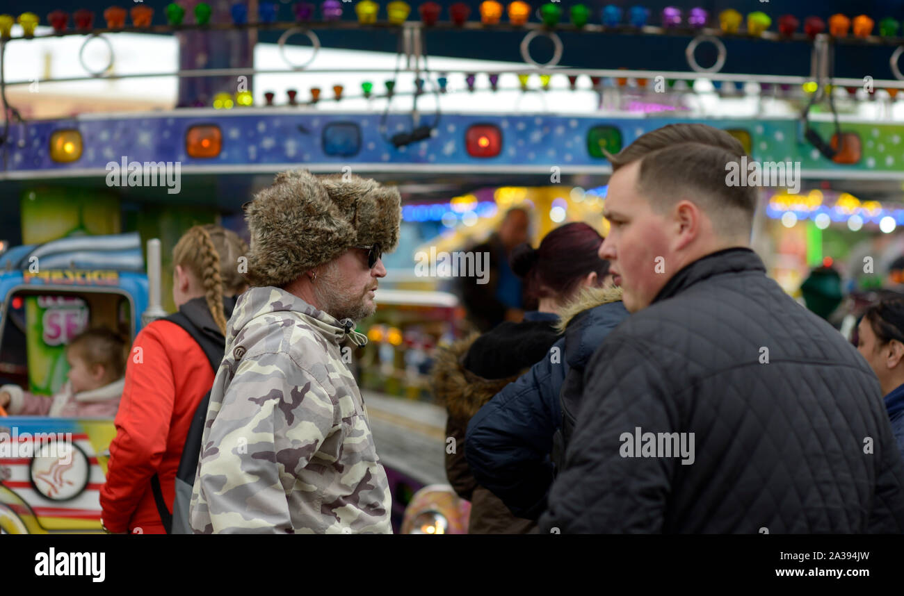 Mann in furry Hut & camouflage Jacke, im Gespräch mit anderen, an Goose Fair. Stockfoto