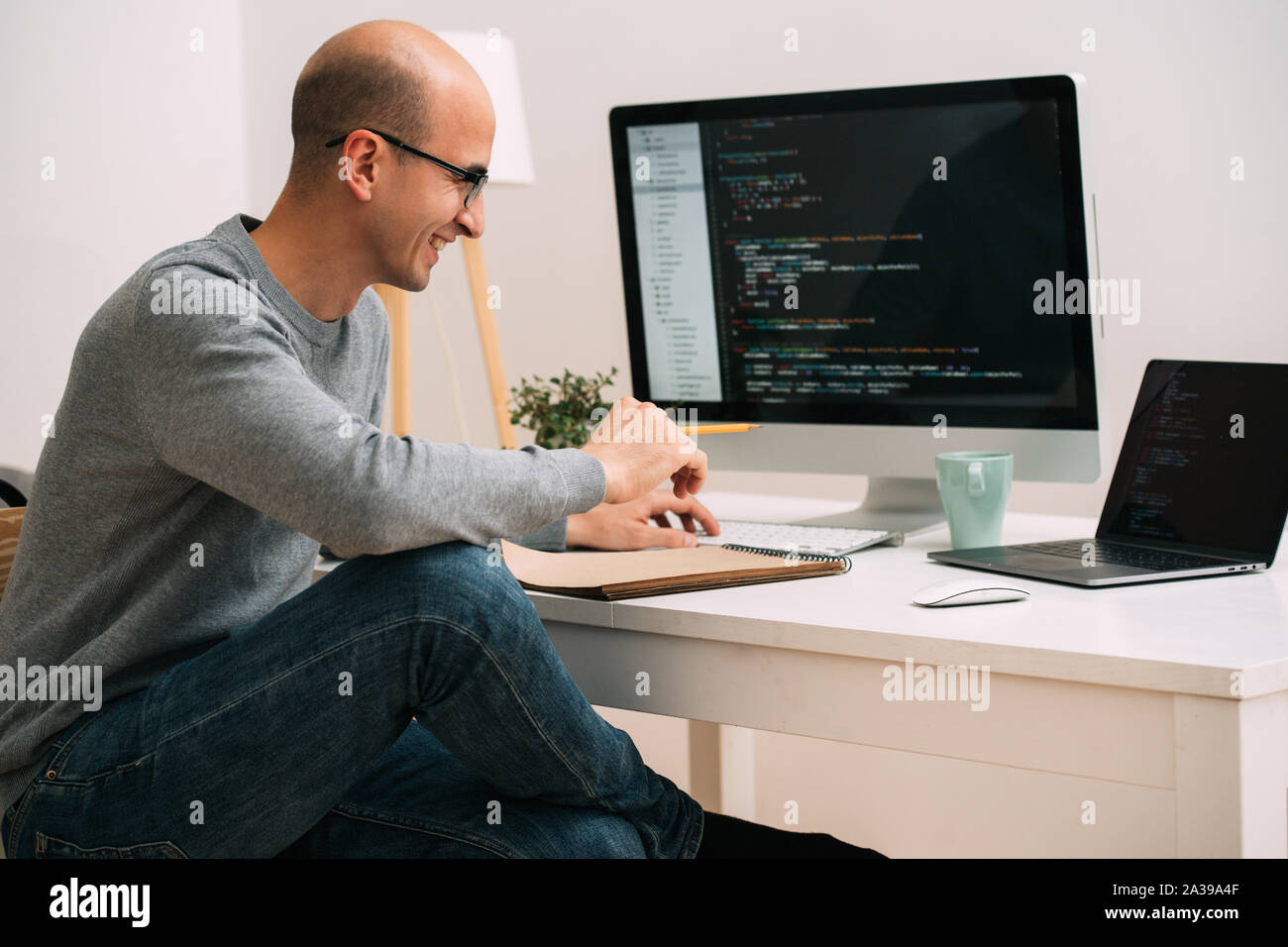 Programmierer, die Arbeit hinter dem Schreibtisch, die Analyse von Code auf dem schwarzen Bildschirm. Stockfoto