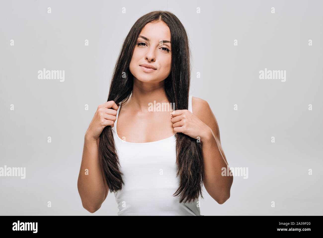 Brunette schöne Frau mit langen, geraden gesundes und glänzendes Haar isoliert auf Grau Stockfoto