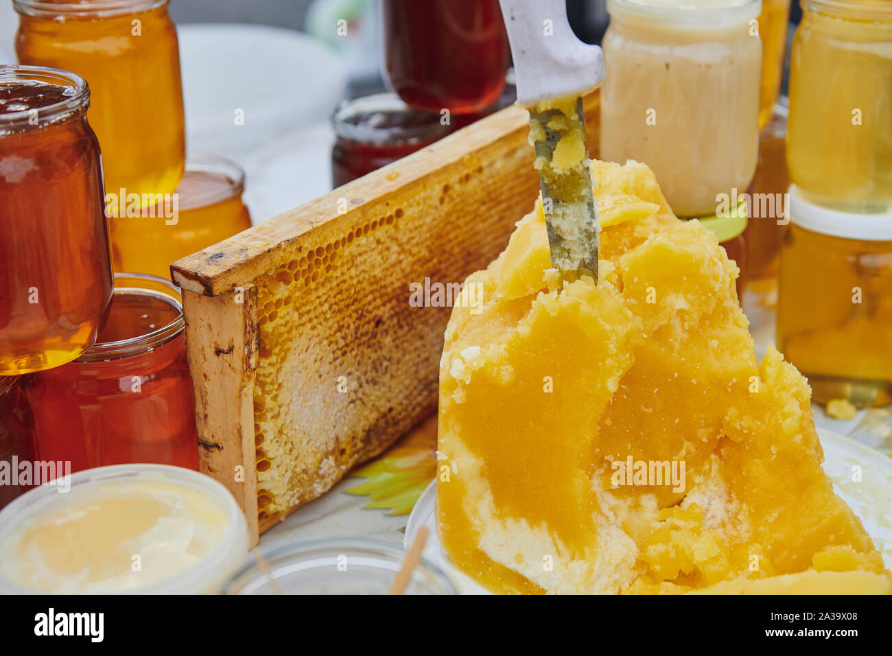 Eine Menge Honig Produkte auf dem Markt. Gläser mit verschiedenen Sorten von Honig. Das Messer ragt aus Honig. Honey Farm Produkte. Stockfoto