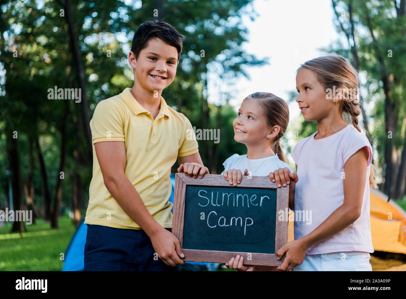 Fröhliche Kinder holding Kreidetafel mit Summer Camp Buchstaben Stockfoto