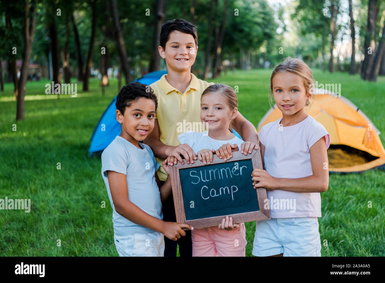 Fröhlich multikulturellen Kinder holding Kreidetafel mit Summer Camp Buchstaben Stockfoto